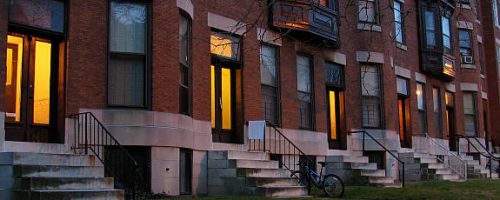 Warm light emanates from a row of doorways at dusk.  Charles Village, Baltimore, MD.
